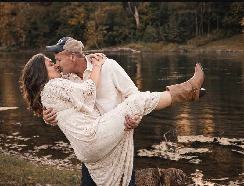Anniversary couple sharing a playful kiss by the river