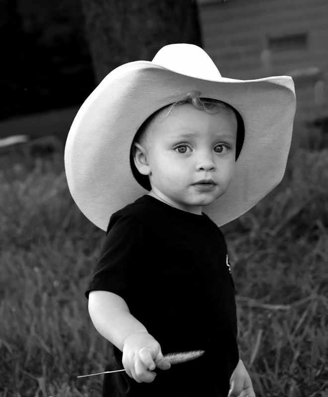 Close black and white portrait of a young boy in a cowboy hat