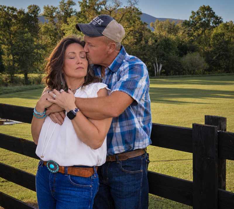 Couple embracing by a black fence in warm evening light