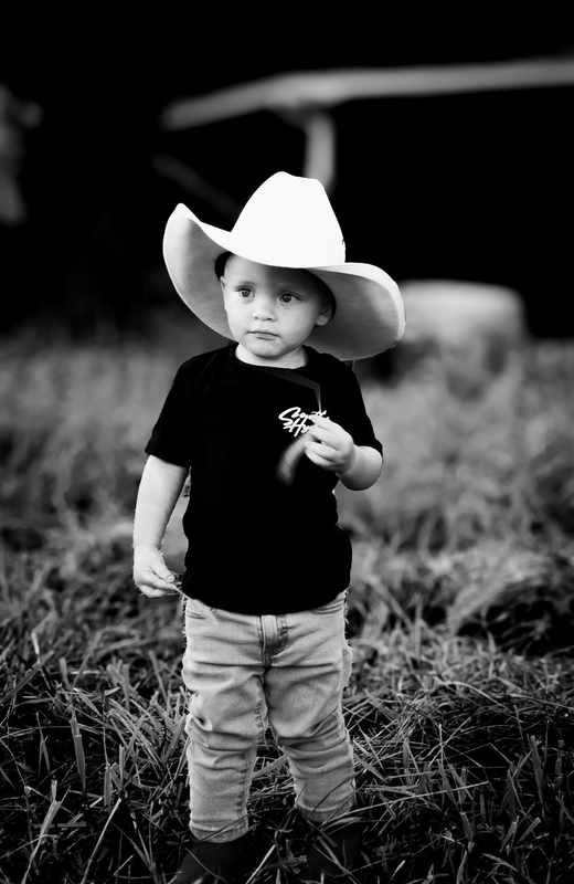Young boy wearing a cowboy hat in a black and white portrait