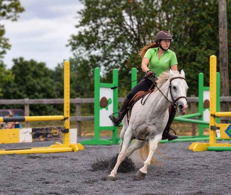 Gray horse and rider turning through the arena after a jump